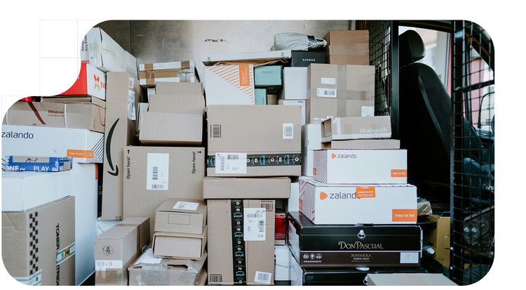 Furgoneta de reparto estacionada con la puerta trasera abierta, mostrando el interior lleno de cajas apiladas.