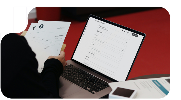 Persona comprobando facturas de su negocio, en papel y en su ordenador